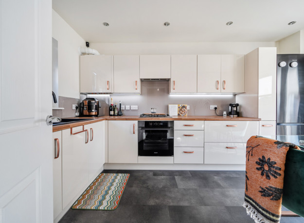 White kitchen with integrated appliances, dining table and tiled floor.