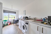 Kitchen with appliances, worktops, dining table with chairs and window.