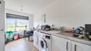 Kitchen with appliances, worktops, dining table with chairs and window.