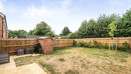 Back garden with grass lawn, wooden fence, shed, and surrounding trees.