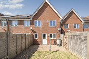 Enclosed rear garden with patio doors, fencing and neighbouring brick houses