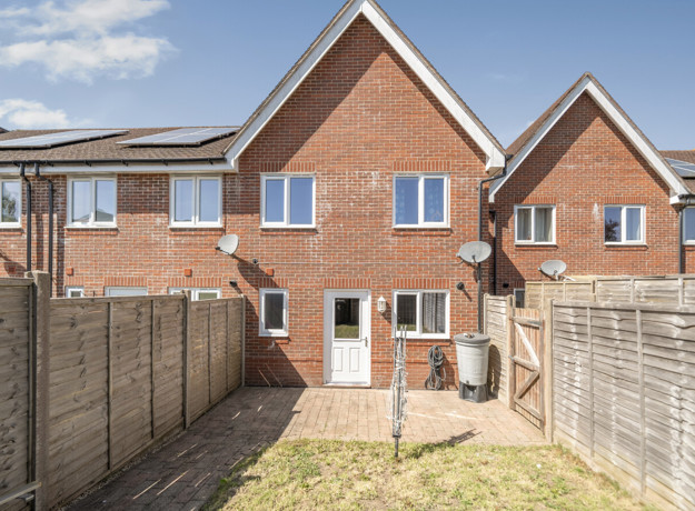 Enclosed rear garden with patio doors, fencing and neighbouring brick houses