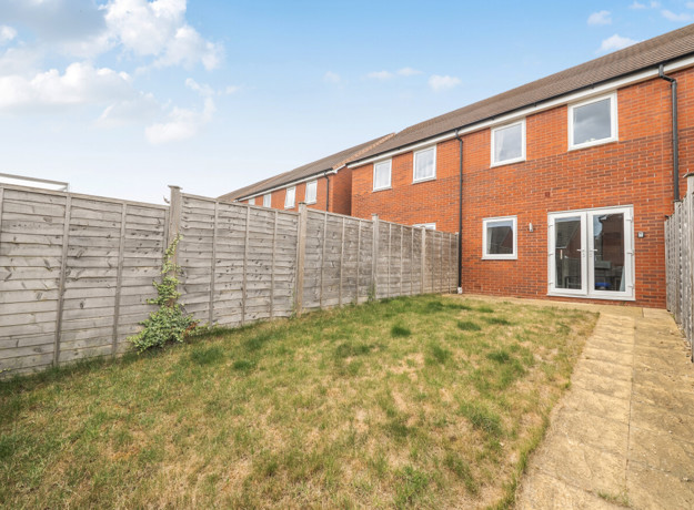 Rear garden with lawn, paved path and fenced boundaries.