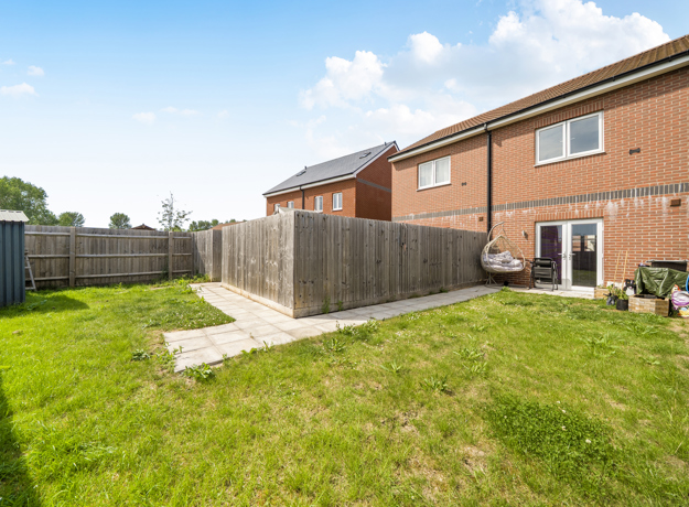 Rear garden with lawn, patio area and surrounding fencing.