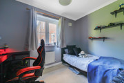 Single bedroom set up with bed, desk, shelving and window overlooking neighbouring buildings