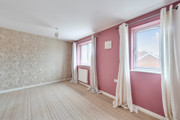 Living room with patterned wallpaper, pink walls, and windows with light curtains.