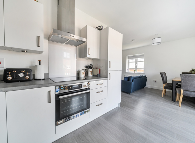 Open plan kitchen and dining area with appliances, table, and chairs visible.