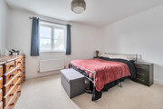 Bedroom with bed, chest of drawers, wardrobe and window with curtains.