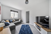Living room with grey sofa, TV unit, and window with natural light.