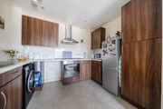 Kitchen with wooden-effect cabinets, tiled floor, countertops and appliances.