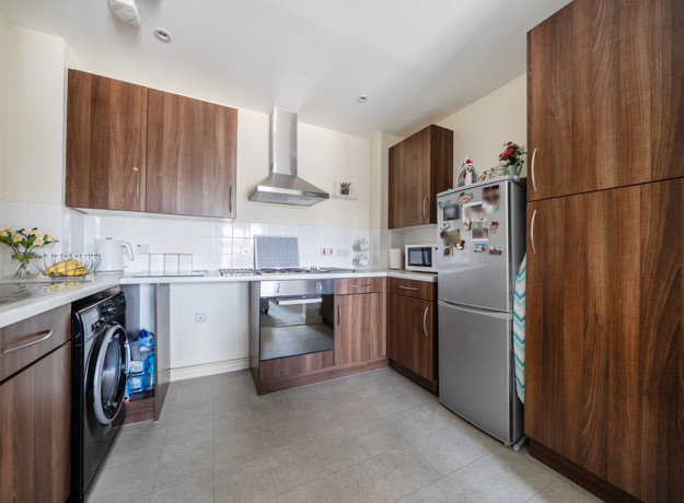 Kitchen with wooden-effect cabinets, tiled floor, countertops and appliances.