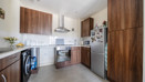 Kitchen with wooden-effect cabinets, tiled floor, countertops and appliances.