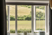 View through a window overlooking open fields and greenery.