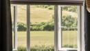 View through a window overlooking open fields and greenery.