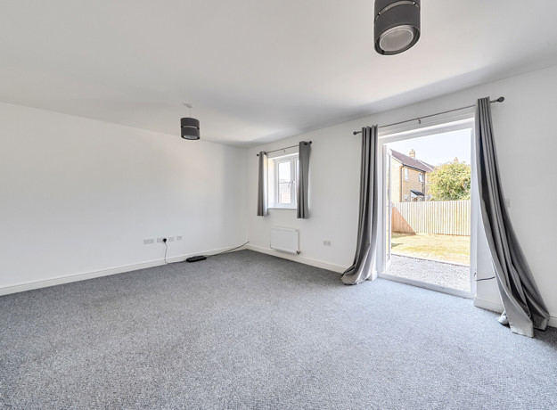 Living area with grey carpet and patio doors to the garden.