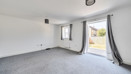 Living area with grey carpet and patio doors to the garden.