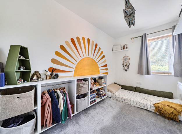 Bedroom with sun mural, storage, floorbed and window.