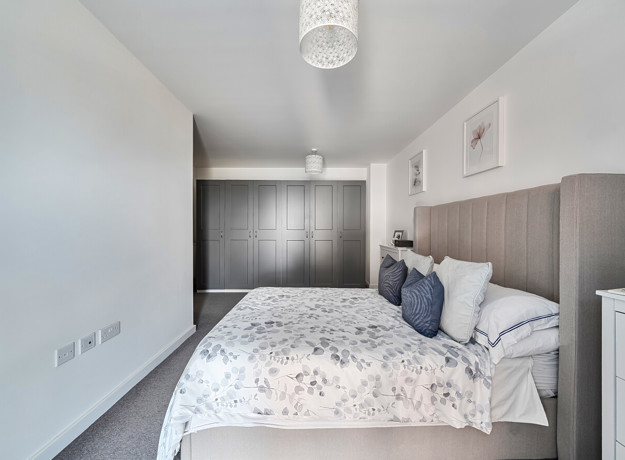 Bedroom with double bed, bedside tables and fitted wardrobe doors.