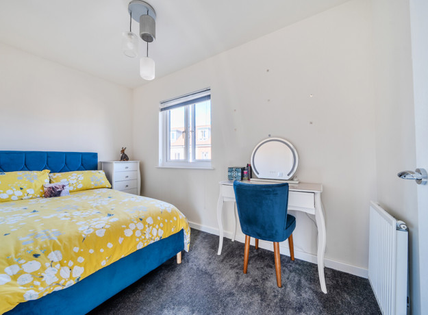 Bedroom with double bed, dressing table, chair and window.