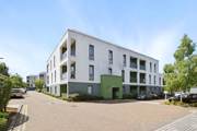 Apartment building exterior with windows, balconies, and paved walkway.
