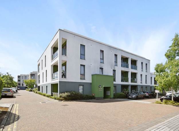Apartment building exterior with windows, balconies, and paved walkway.