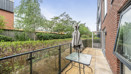 Balcony with glass railing, table, chair, and garden view.