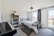 Bedroom with a double bed, shelving unit, keyboard and windows.