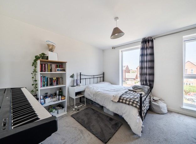 Bedroom with a double bed, shelving unit, keyboard and windows.