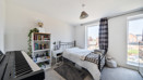 Bedroom with a double bed, shelving unit, keyboard and windows.