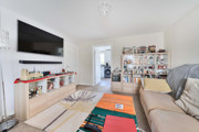 Living room with sofas, a wall-mounted television and shelving.