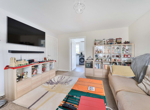 Living room with sofas, a wall-mounted television and shelving.