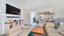 Living room with sofas, a wall-mounted television and shelving.