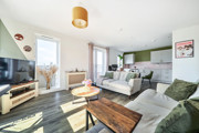 Living area with sofas, coffee table, television, and windows and kitchen in the background.