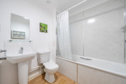 Bathroom with bathtub, toilet, sink, and wall mirror.