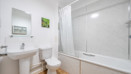 Bathroom with bathtub, toilet, sink, and wall mirror.