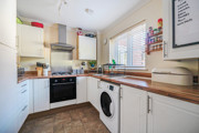 Fitted kitchen with white cabinets, wooden worktops, appliances and tiled flooring