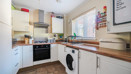 Fitted kitchen with white cabinets, wooden worktops, appliances and tiled flooring