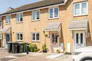 Terraced brick houses with front doors, windows and wheelie bins along a paved street.