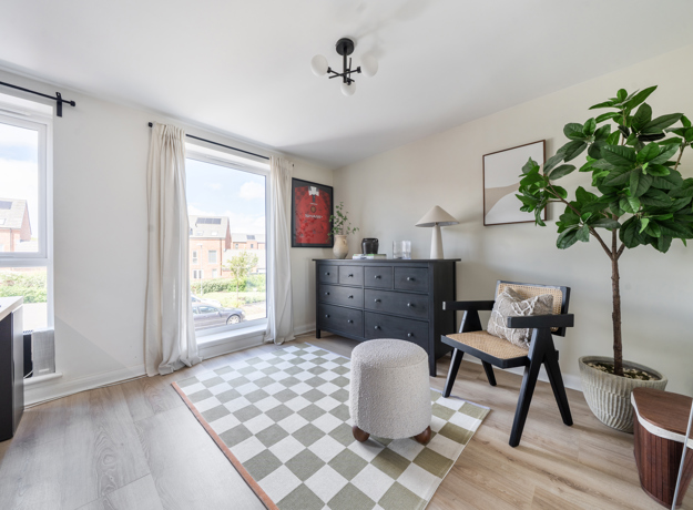 Second bedroom with desk, chair, patterned floor, plants, and large window.
