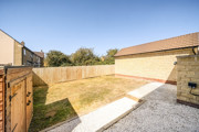 Enclosed rear garden with lawn and gravel area.