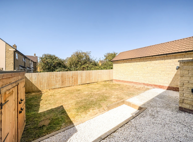 Enclosed rear garden with lawn and gravel area.