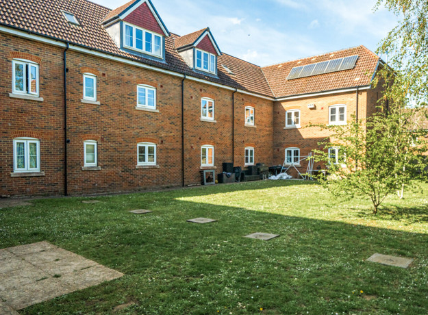 Communal garden with lawn area surrounded by brick apartment buildings