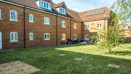 Communal garden with lawn area surrounded by brick apartment buildings