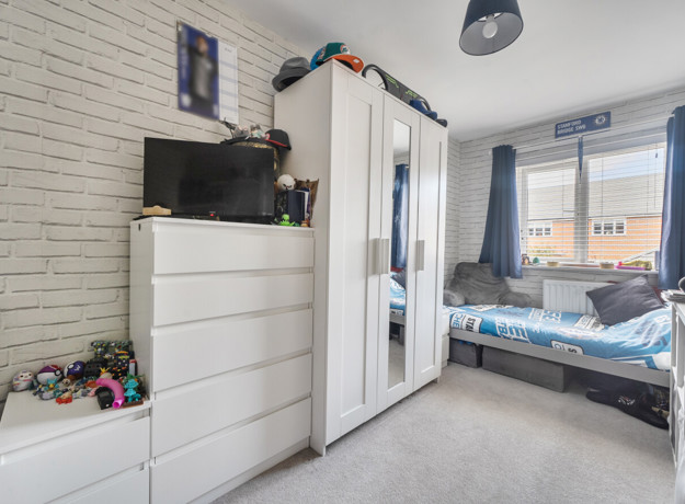Bedroom with children's bed, wardrobe, dresser, and window with blinds.