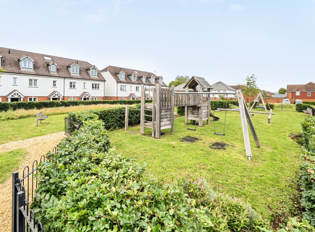 Residential area with grass, play structure and houses in background.