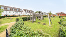 Residential area with grass, play structure and houses in background.