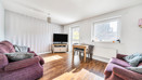 Bright living room with wooden-effect flooring, sofas, large window and TV unit