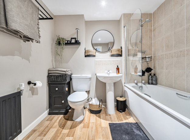Bathroom with a bath, toilet, sink, mirror and tiled walls.