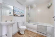 Bathroom with bath, shower, sink, toilet and tiled walls.