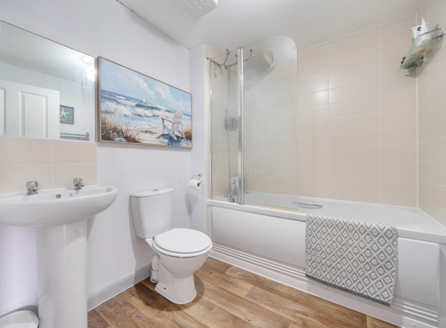 Bathroom with bath, shower, sink, toilet and tiled walls.